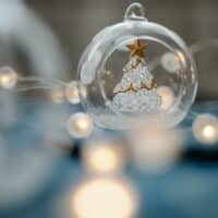 Glass Christmas tree inside transparent ball surrounded by burning garland for festive decorations